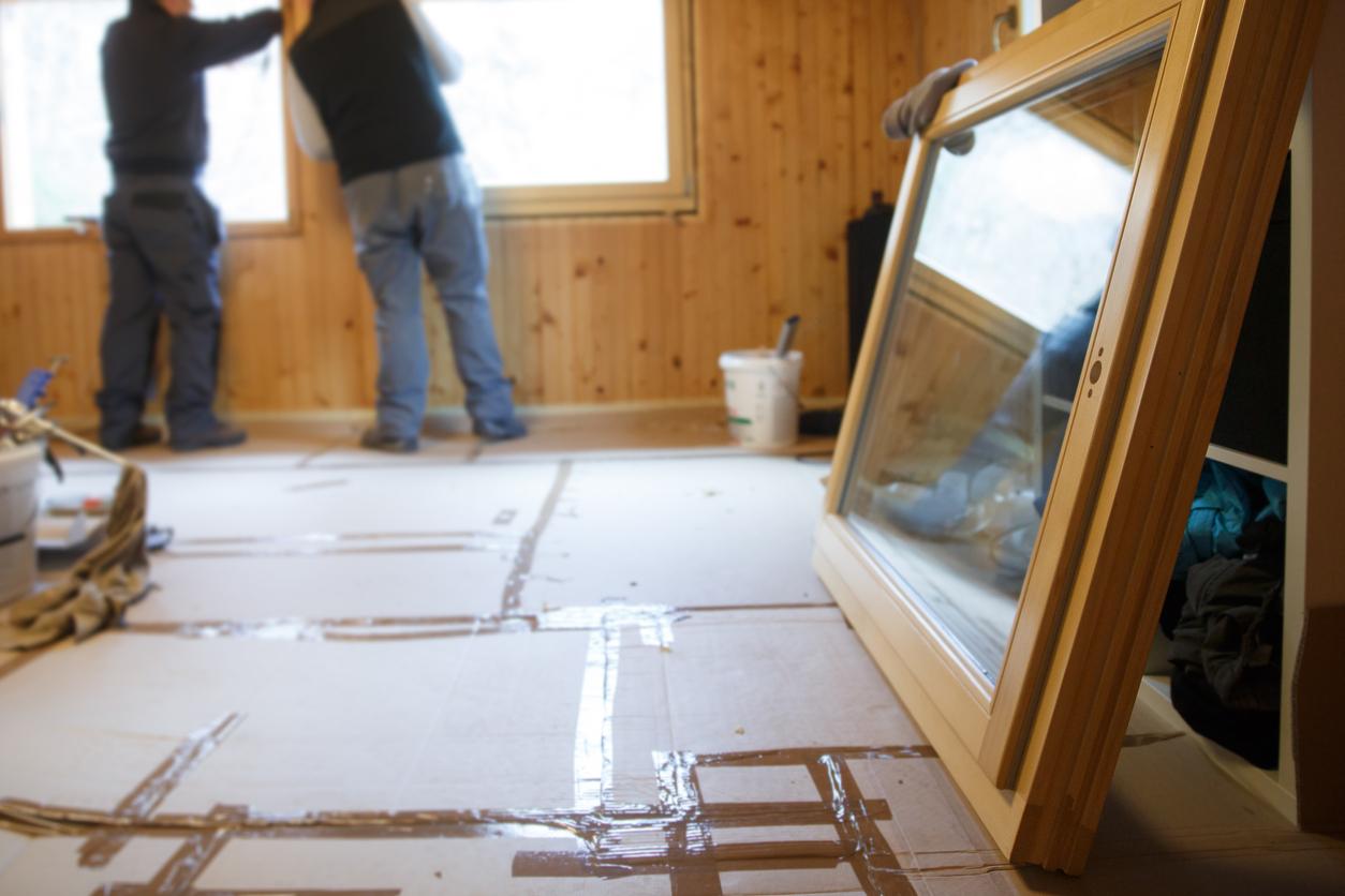 Der Boden des Holzhauses wird abgedeckt beim Ersetzen der Fenster