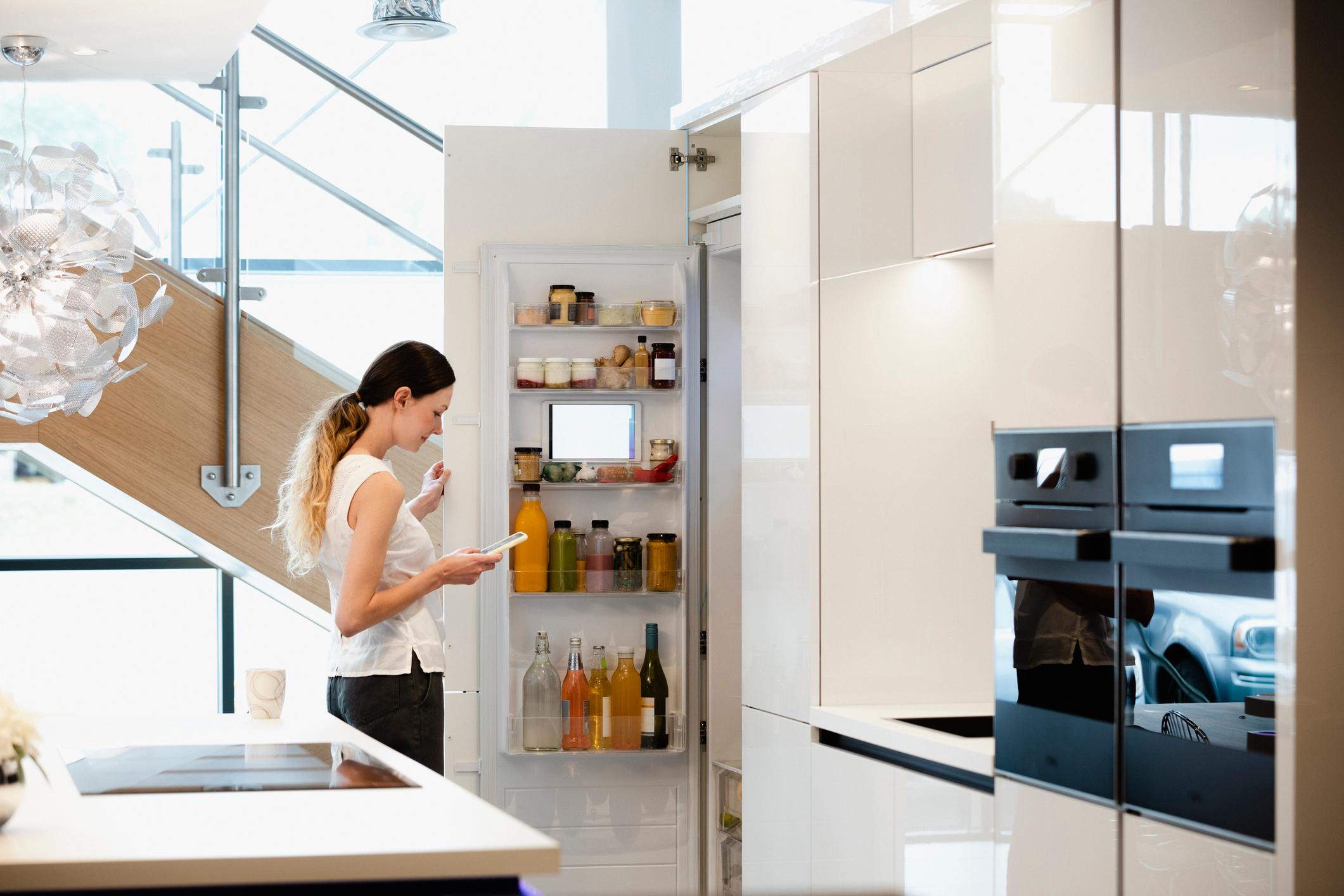 Eine Frau vernetzt Ihre Küche mit dem Smartphone.